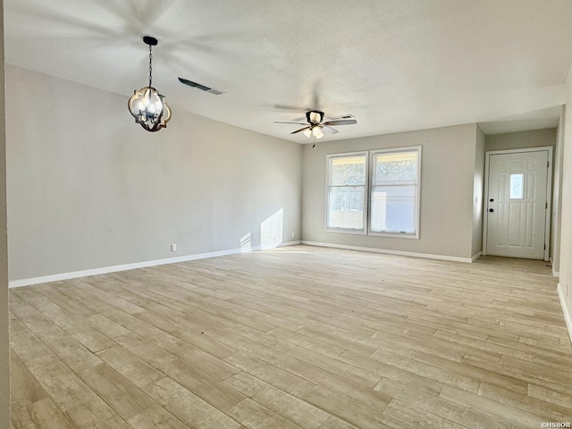 unfurnished living room with visible vents, baseboards, light wood-style flooring, a textured ceiling, and ceiling fan with notable chandelier