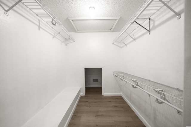 walk in closet featuring wood finished floors and attic access