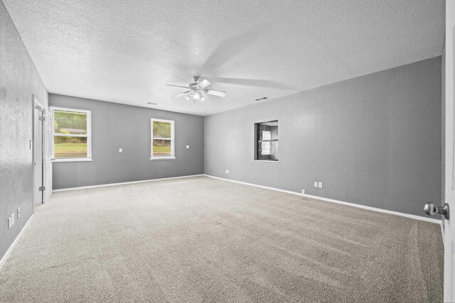 carpeted empty room with ceiling fan, a textured ceiling, and baseboards