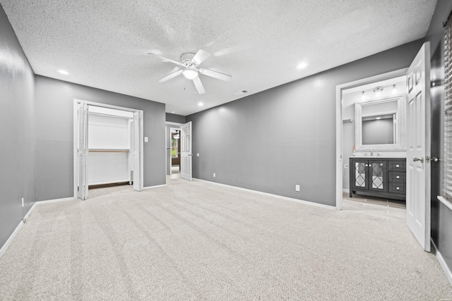 unfurnished bedroom with carpet floors, a textured ceiling, baseboards, a sink, and a ceiling fan