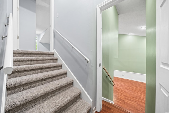 stairway with wood finished floors and baseboards