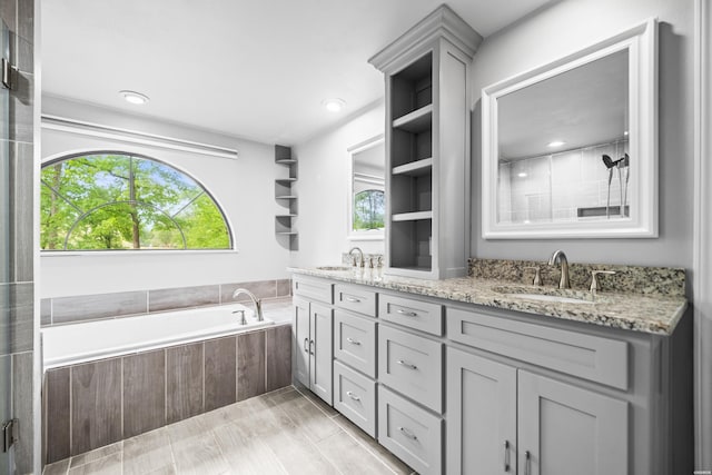 full bath with double vanity, a garden tub, and tiled shower