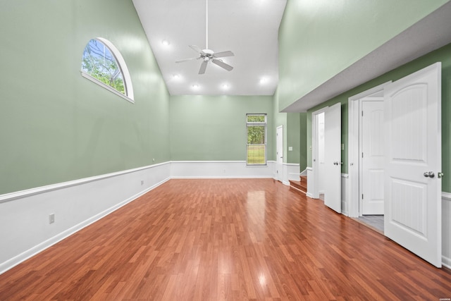 unfurnished room featuring high vaulted ceiling, ceiling fan, wood finished floors, and baseboards