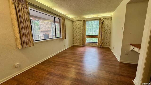 unfurnished room with a textured ceiling, dark wood finished floors, and baseboards