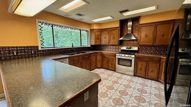 kitchen with stainless steel gas stove, wall chimney range hood, dark countertops, and a sink