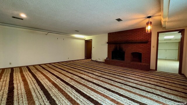 unfurnished living room featuring a textured ceiling, a fireplace, carpet flooring, and visible vents