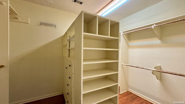 walk in closet featuring dark wood-style flooring and visible vents