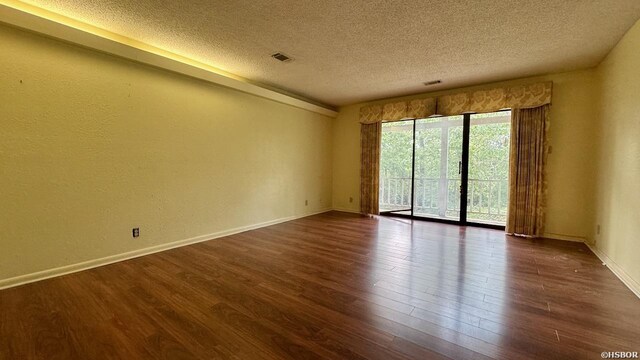 unfurnished room featuring visible vents, a textured ceiling, baseboards, and dark wood-style flooring