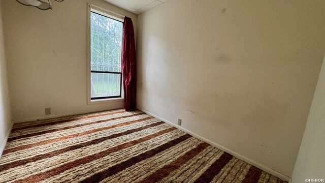 spare room with a healthy amount of sunlight, light carpet, and baseboards