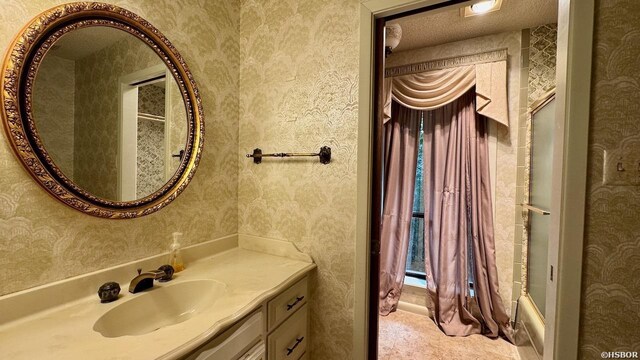 full bath featuring a textured ceiling, shower / bath combination, vanity, and wallpapered walls