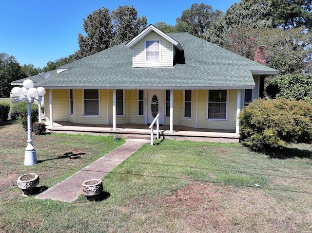 view of front of home featuring a fire pit, a porch, roof with shingles, and a front yard