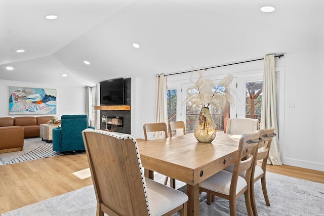 dining room with lofted ceiling, a large fireplace, light wood finished floors, and recessed lighting