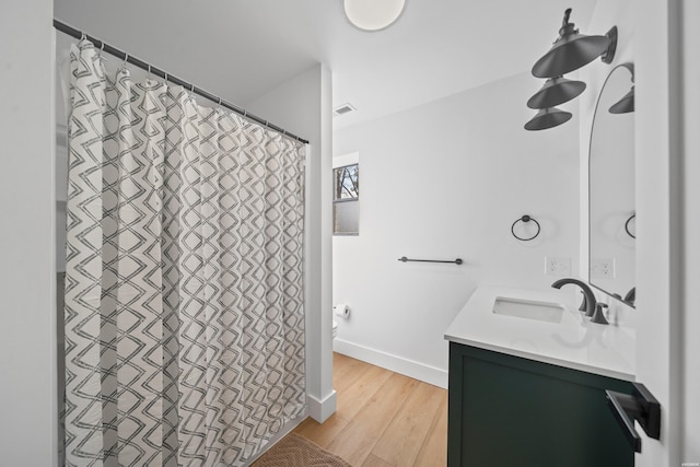 bathroom with visible vents, baseboards, wood finished floors, and vanity