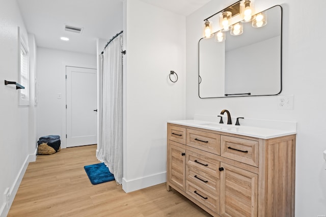 bathroom with visible vents, wood finished floors, vanity, and baseboards