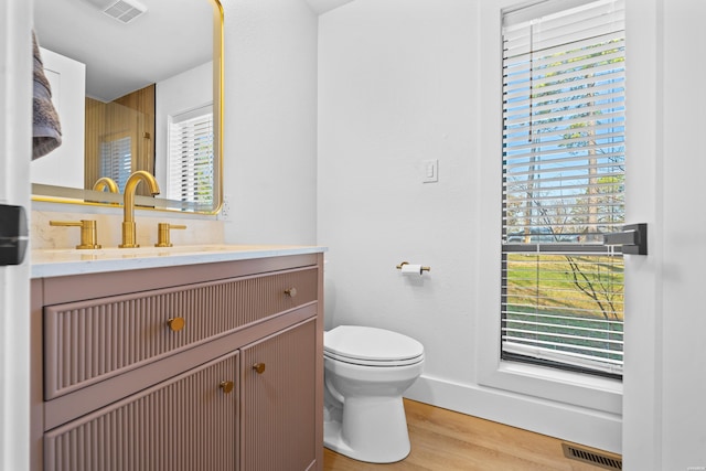 bathroom featuring toilet, visible vents, wood finished floors, and vanity