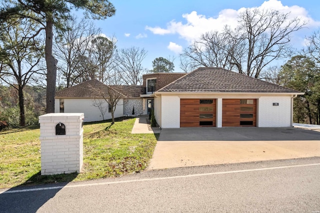 view of front of home featuring an attached garage, roof with shingles, a front yard, and brick siding