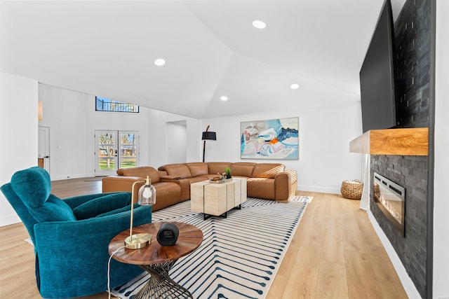 living area featuring a glass covered fireplace, light wood-style flooring, baseboards, and recessed lighting