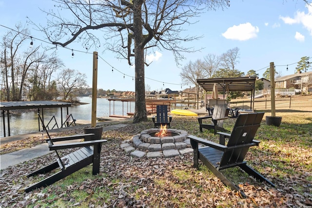 surrounding community featuring an outdoor fire pit, a water view, and fence