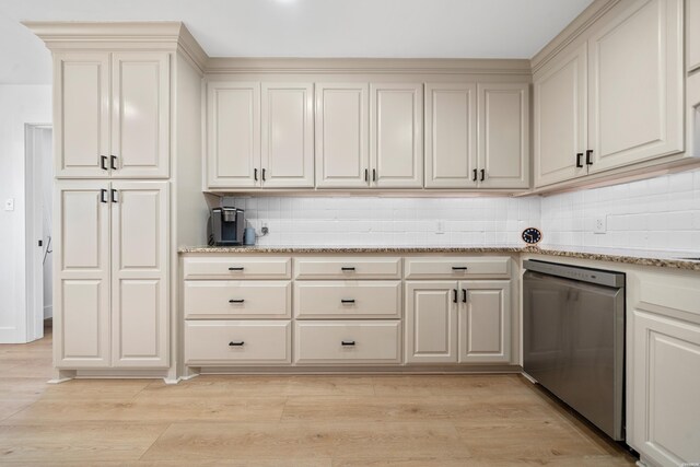 kitchen with dishwasher, light stone counters, light wood finished floors, and backsplash