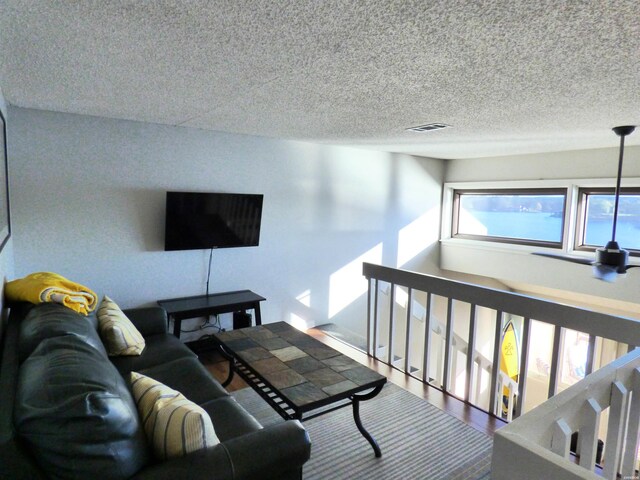 living room with visible vents, a textured ceiling, and wood finished floors