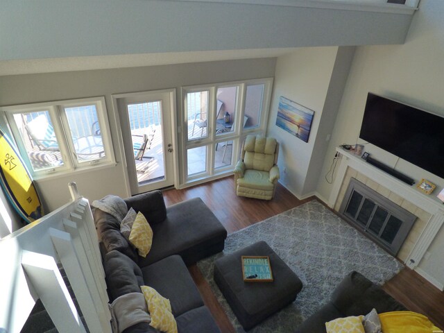 living room with lofted ceiling, a tiled fireplace, wood finished floors, and baseboards