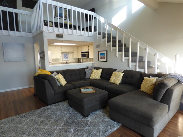 living area with high vaulted ceiling, stairway, and dark wood-style flooring