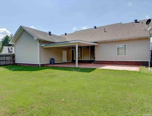 rear view of property featuring a shingled roof, a patio area, a yard, and fence