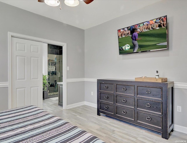 bedroom featuring light wood finished floors, ensuite bath, a ceiling fan, and baseboards