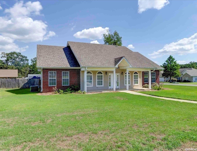 view of front of property featuring a porch, brick siding, fence, and a front lawn