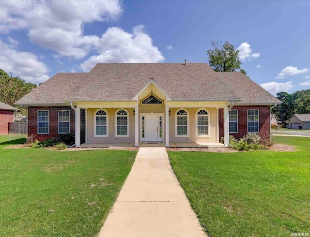 view of front of home featuring covered porch, brick siding, a front lawn, and roof with shingles