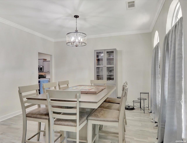 dining space featuring baseboards, visible vents, crown molding, and light wood finished floors