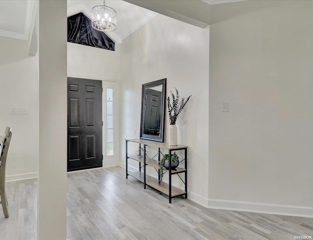 foyer featuring a notable chandelier, crown molding, light wood-style flooring, and baseboards