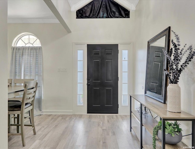 foyer featuring baseboards, light wood-type flooring, and crown molding