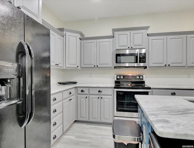 kitchen featuring tasteful backsplash, light wood-style flooring, appliances with stainless steel finishes, gray cabinets, and light countertops