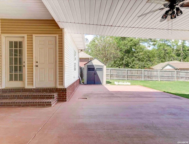 view of patio / terrace featuring entry steps, ceiling fan, a fenced backyard, an outdoor structure, and a storage unit