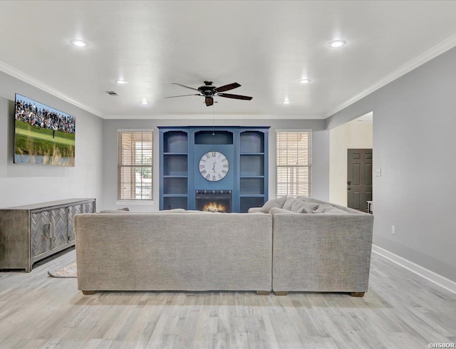 unfurnished living room with light wood finished floors, a lit fireplace, and crown molding