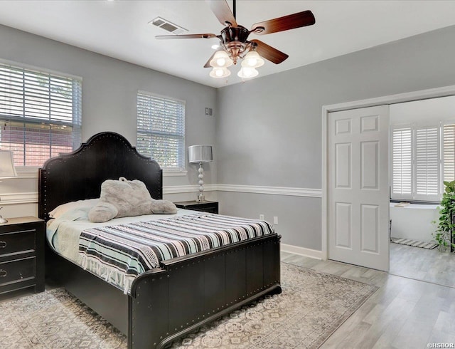 bedroom featuring visible vents, multiple windows, ceiling fan, and light wood-style flooring