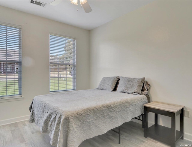 bedroom with light wood finished floors, baseboards, visible vents, and a ceiling fan