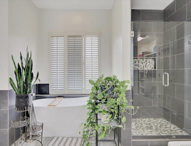 bathroom with a soaking tub and a shower stall