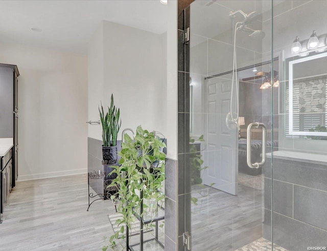 bathroom with wood finished floors, a shower stall, and vanity