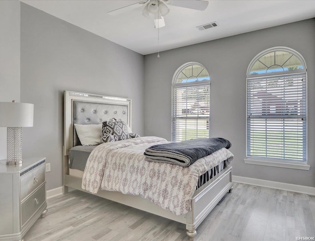 bedroom with light wood finished floors, visible vents, baseboards, and a ceiling fan