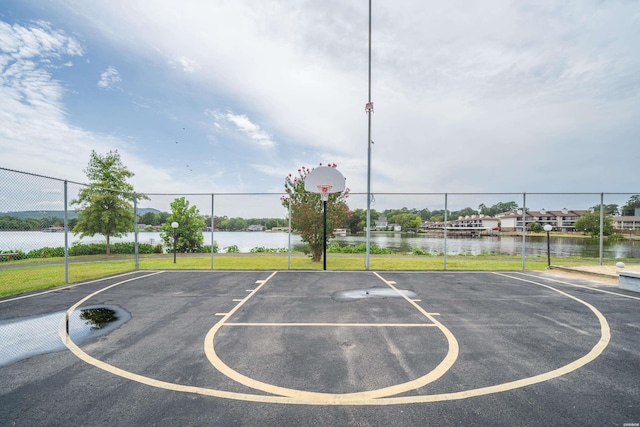 view of basketball court featuring community basketball court, a water view, and fence