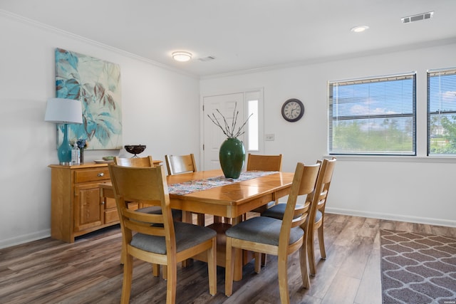 dining room with ornamental molding, wood finished floors, visible vents, and baseboards