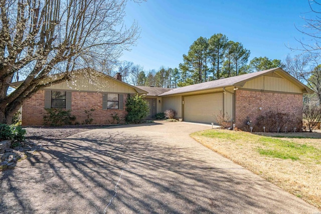 single story home featuring brick siding, an attached garage, a chimney, and driveway