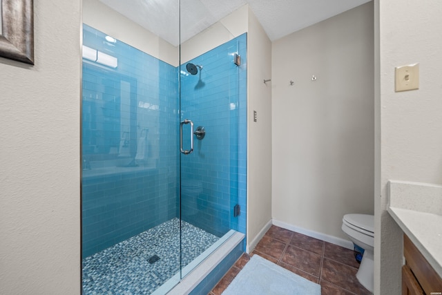 bathroom featuring toilet, a shower stall, vanity, baseboards, and tile patterned floors