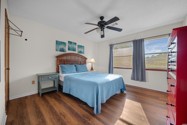 bedroom with a textured ceiling, dark wood-type flooring, visible vents, and baseboards