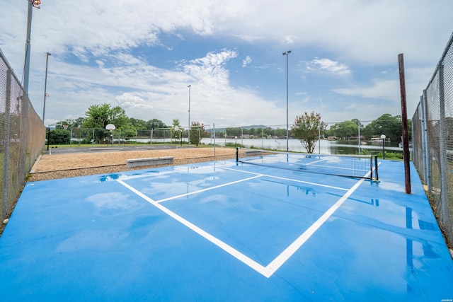 view of sport court with a water view and fence