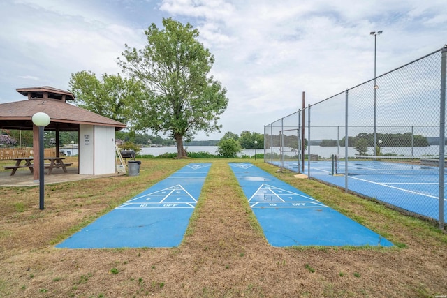 surrounding community with a tennis court, shuffleboard, and fence