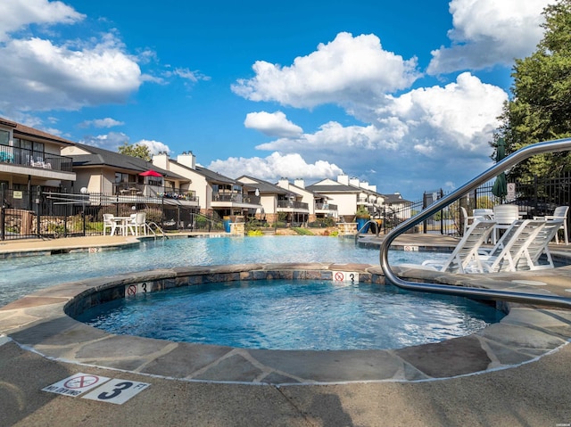 pool featuring a community hot tub, fence, and a residential view