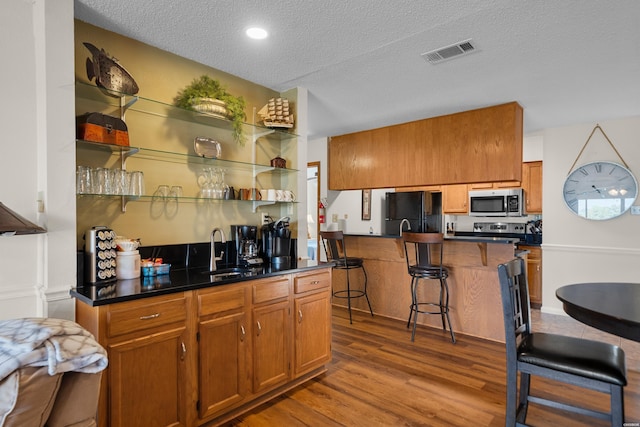 kitchen featuring stainless steel appliances, dark countertops, visible vents, and open shelves